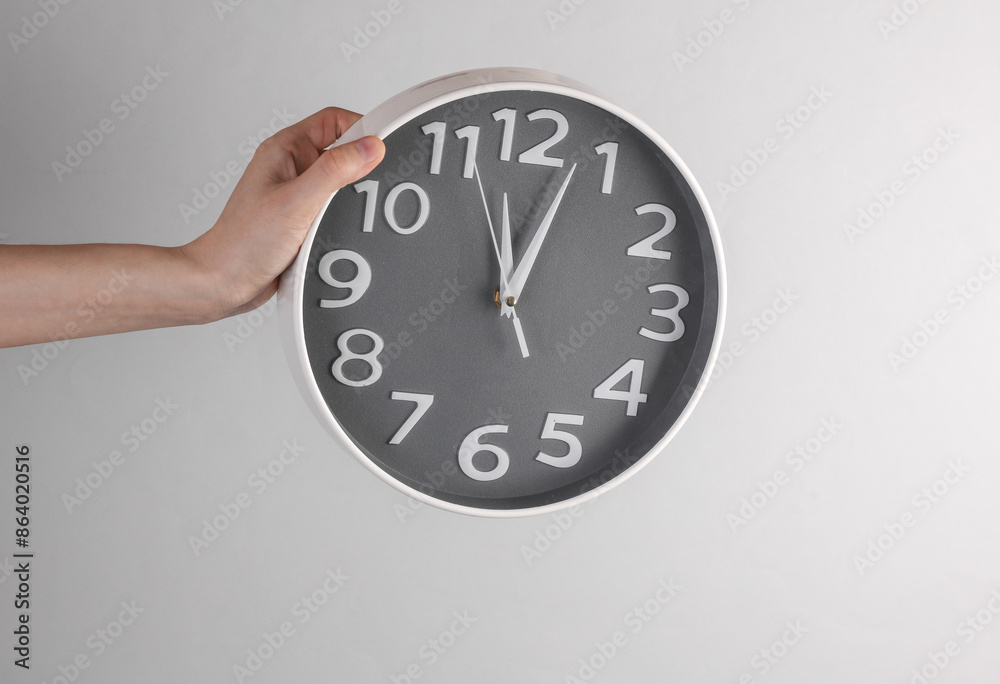 Poster Hand holds a large clock on a gray background