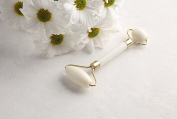 Bouquet of flowers with white jade massage roller on concrete background