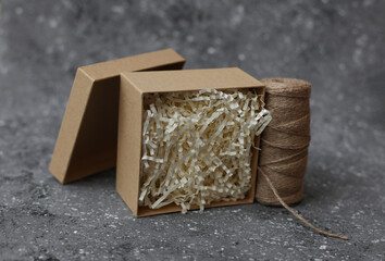 Cardboard craft box with filler and a skein of thread on a concrete background