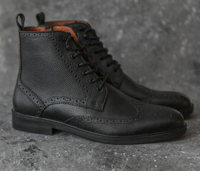 Men's black leather brogue boots on concrete background