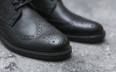 Men's black leather brogue boots on concrete background