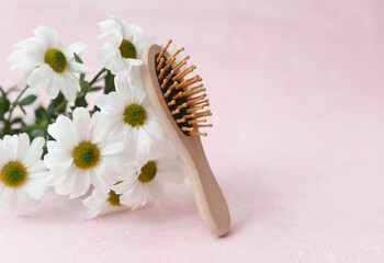 Eco hair brush with a bouquet of flowers on a pink concrete background