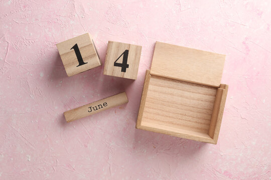 Wooden block calendar with date June 14 on pink concrete background