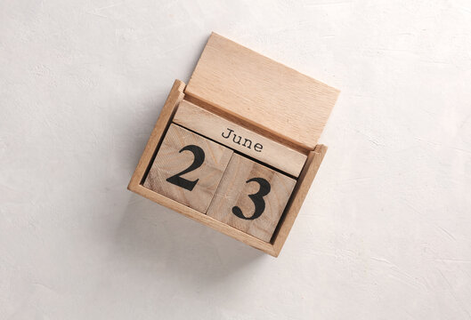 Wooden block calendar with date June 23 on white concrete background