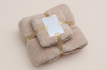 Set of towels with a tag wrapped in ribbon on beige background