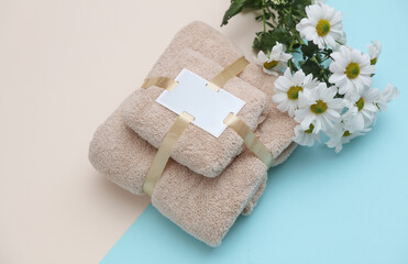Set of towels with a tag wrapped in ribbon and flowers on a blue beige background