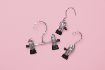 Hangers for pants or trousers on a pink concrete background