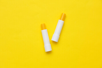 Lip balm tubes on yellow background. Top view