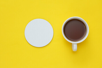 Mockup of white empty coaster and coffee cup on a yellow background