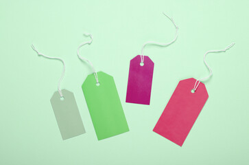 Colored Blank clothing price tags or labels mockup with strings on green background. Sale, shopping...