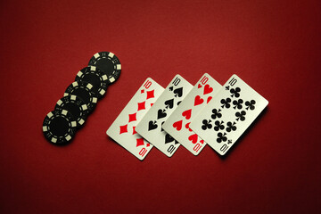 Luck in a card game of poker with a winning combination of four of a kind or quads. Playing cards and chips are laid out in a club on a red table