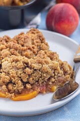 Peach Crisp or cobbler with brown sugar and oat streusel on plate, vertical, closeup