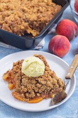 Delicious Peach Crisp or cobbler on plate with scoop of vanilla ice cream, vertical