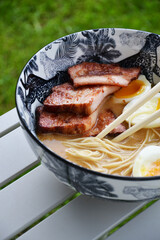 Bowl of miso ramen soup on table outside outdoor on patio lawn garden