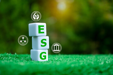 A group of three white cubes with the letters ESG written on them, The cubes are placed on a green...