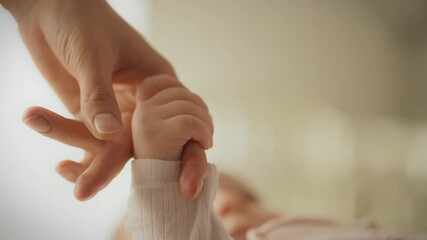 The baby's tiny hand squeezes his mother's finger, reflecting the mother's love and care. The child seeks mother’s affection and warmth for a sense of security