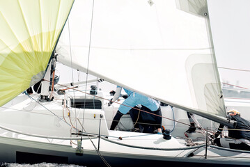 Sailboat crew members are working hard adjusting sails during a regatta
