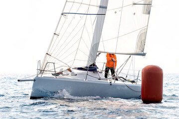 Competitive regatta sees sailing team maneuvering around a buoy on their sailboat