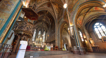 The interior of Basilica of Sts Peter and Paul with frescoes on the walls and ceiling and an ornate wooden pulpit. Prague, Czech Republic