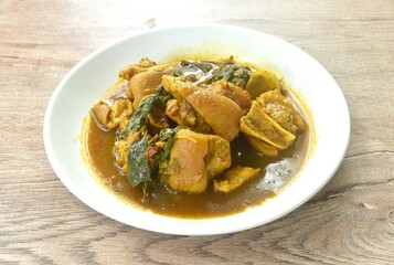 spicy boiled chop pork leg with cumin basil in coconut milk curry soup on plate 
