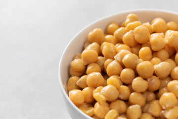 Canned chickpeas in small bowl on light grey background