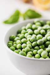 A bowl of frozen green peas on a white background. Fresh and healthy vegetable