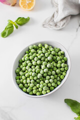A bowl of frozen green peas on a white background. Fresh and healthy vegetable