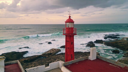 Beautiful lighthouse shining rocky ocean coast at dusk. Historic beacon flashing