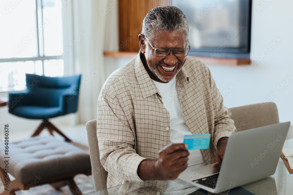 Wall mural senior man using laptop for online banking at home