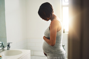 Pregnant, woman and looking at belly by mirror for progress, peace or love in bathroom. Maternity, girl or prenatal care at home for transformation, body or thinking of future in parenthood with baby