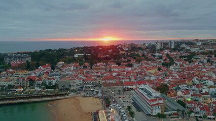 Sunrise illuminate coastal cityscape aerial view. Morning descending on sea
