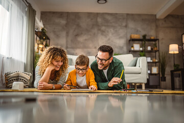 Family of three lie down on the carpet and draw at home together