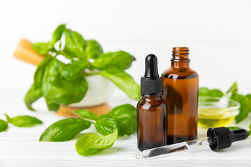 Basil essential oil on a textured wooden background. Basil essential oil and fresh leaves. Aromatherapy. Aroma oil. Medical herbs. Alternative medicine. Place for text. Copy space.