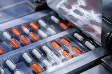 automated medicine packaging machine for orange and white capsules. Pharmaceutical production line...