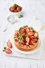 Strawberry cake. Homemade and delicious strawberry sponge cake with fresh summer fruits served, cream cheese frosting and sugar powder on white marble stand and wooden table. Summer berry dessert.