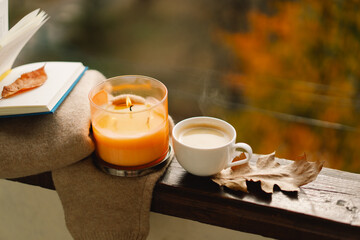 Sweet Home. Still life details in home on a wooden window. Sweater, candle, hot coffee and autumn decor. Autumn home decor. Cozy fall mood. Cozy autumn or winter concept.