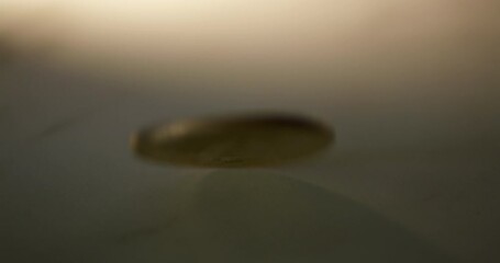 A piece of commemorative golden coin in Thai Baht currency is twirling and slowing down as it lays down on a table.