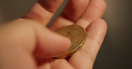 Holding a piece of a commemorative golden Baht coin and flipping it in the person's hand.