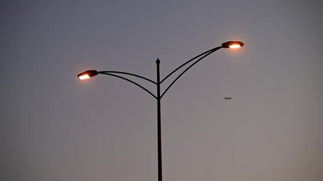 A plane passing behind a streetlight during sunset in the UAE.