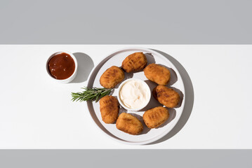 Plato de croquetas fritas con salsa de tomate y mayonesa aperitivo sobre fondo gris. Vista superior	