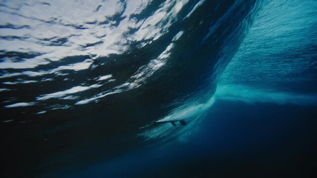 Panning follows underwater view of surfer getting barreled at Cloudbreak Fiji