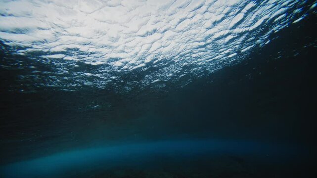 Surface of ocean water at Cloudbreak Fiji gradually turns lighter as wave barrels into vortex underwater