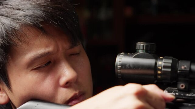 Asian Man Sniper Adjusting and Looking Through Scope Of Rifle Then Shoot, Close Up