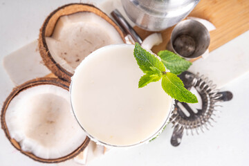 Coconut mint margarita cocktail. Homemade summer cold refreshing coconut milk Lime Margarita with Mint with bar utensils, on white kitchen table