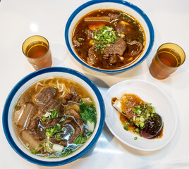Two bowls of Taiwanese beef noodle soup, tofu, century egg and tea, showcasing a delicious and comforting meal made with fresh ingredients in Tainan, Taiwan