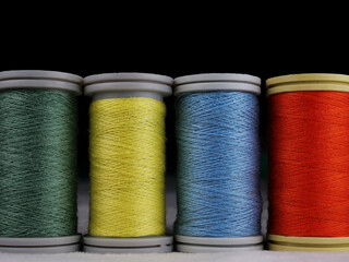 colored spools of threads on black background
