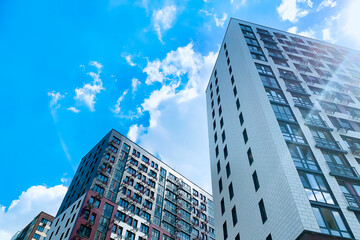 Modern urban architecture showcasing high-rise buildings against a clear blue sky and scattered clouds.