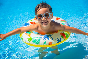 Boy with swim goggles and rubber ring on the pool