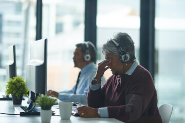 Woman, call center and office in computer with headache, tired and consulting with client. Mature agent, headphones and mic with fatigue for tech support, telemarketing or customer care with burnout