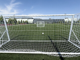 Fototapeta premium Soccer ball on artificial bright and dark green grass at public outdoor football stadium